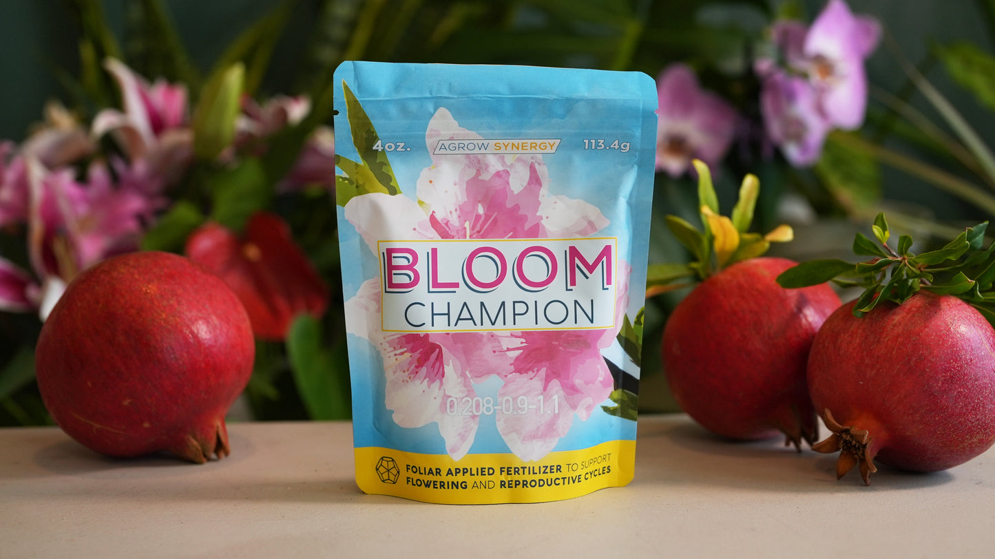 Bloom Champion worm casting fertilizer packet with pomegranates and flowers in the background